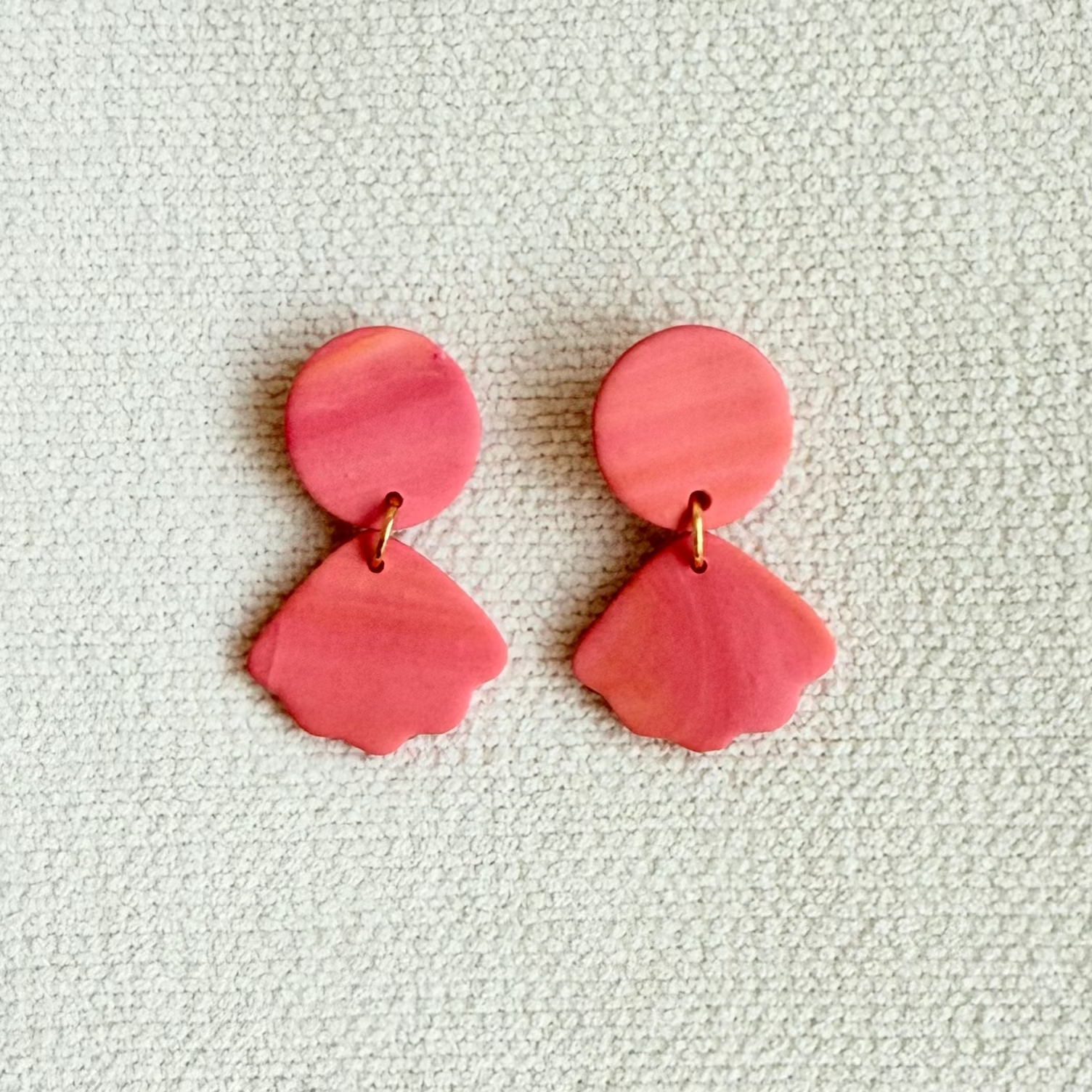 Pair of pink earrings on a textured light gray background