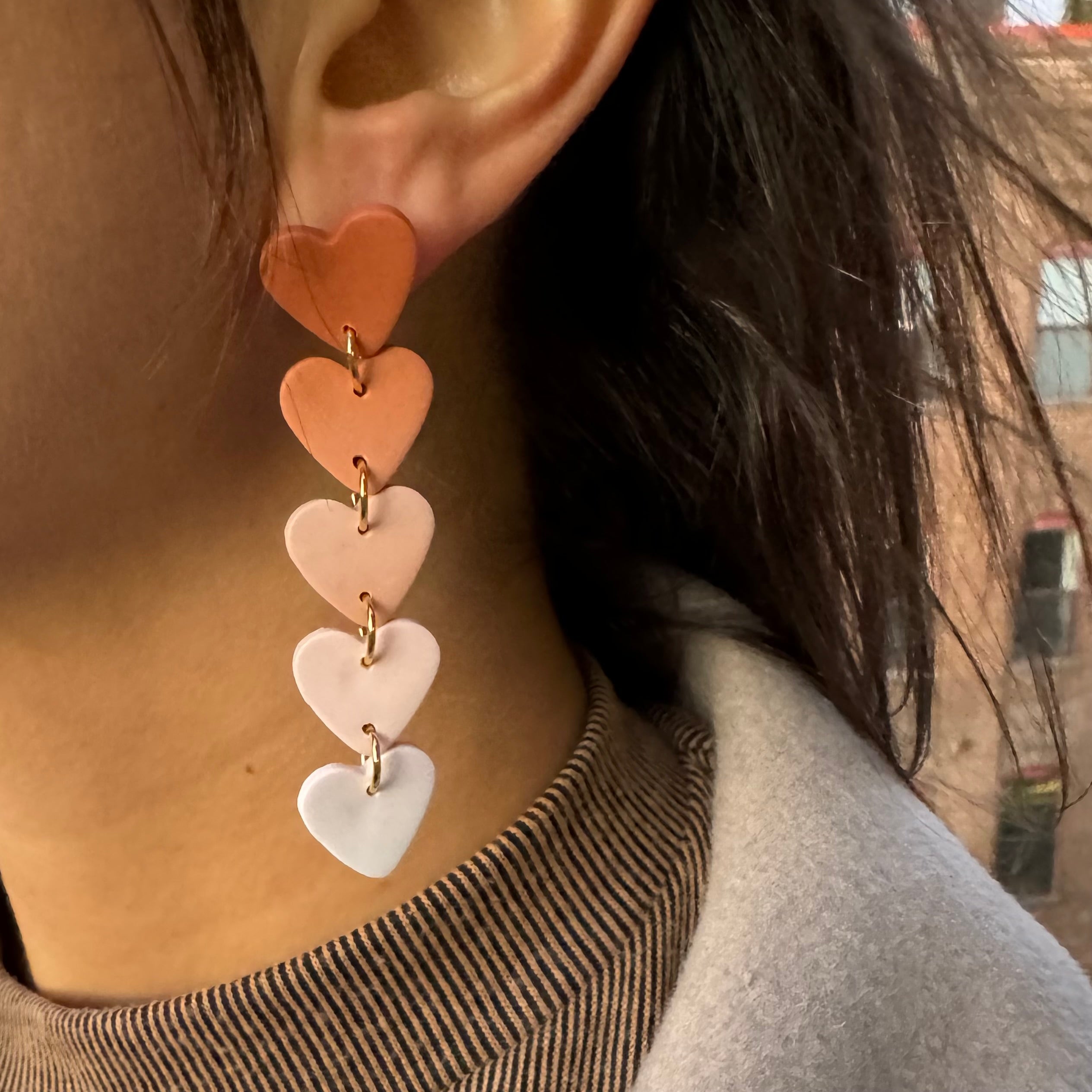 Heart-shaped earrings worn by a person with a blurred background