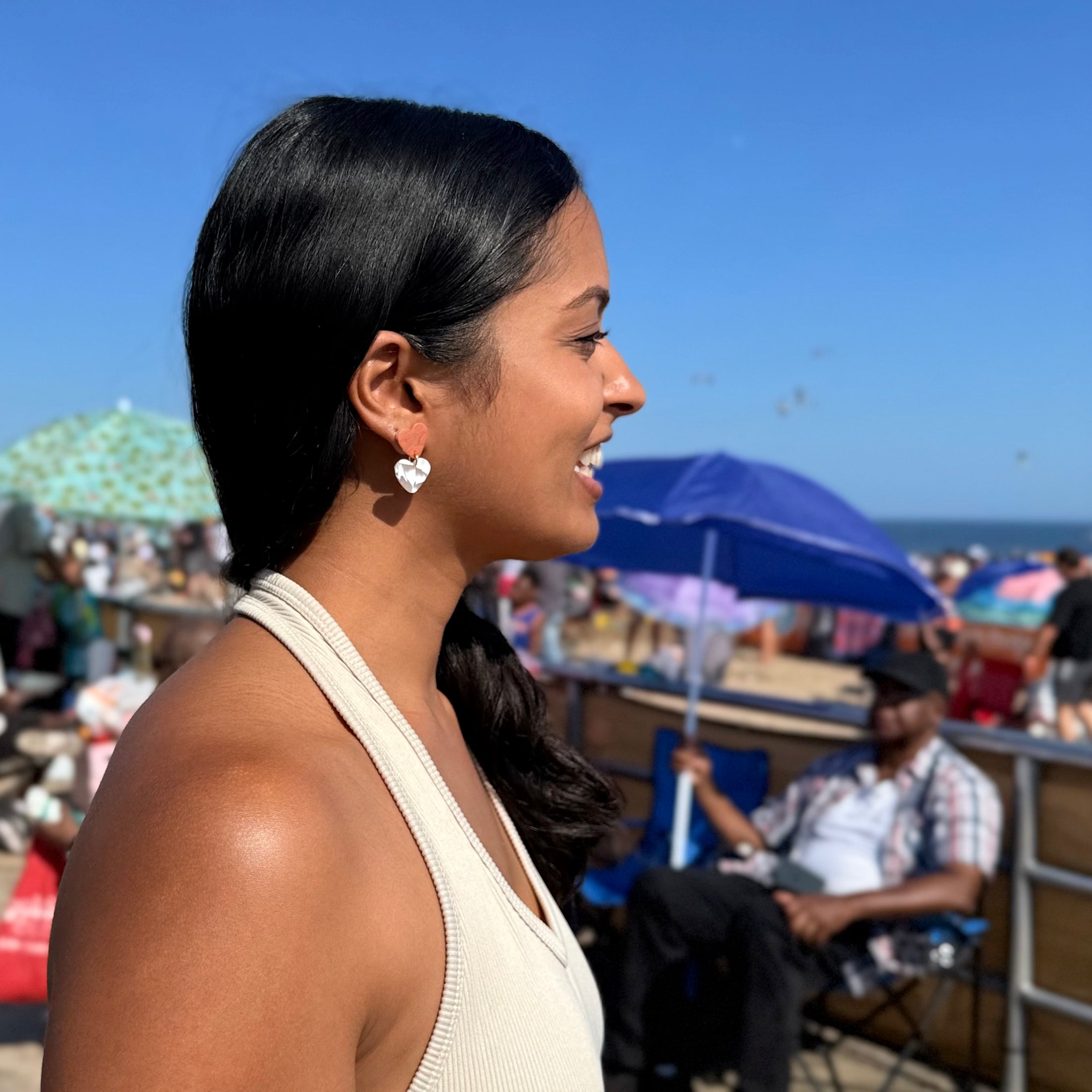 Woman at a beach with umbrellas and people in the background