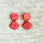 Pair of pink earrings on a textured light gray background